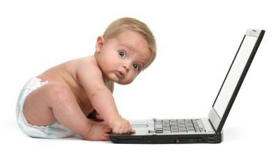 Surprised expression on a baby boys face whilst getting into mischief on a laptop computer